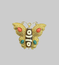 Gold-tone butterfly pendant or brooch featuring a two-eyed Tibetan Dzi bead as the body, accented with red coral and turquoise stones.